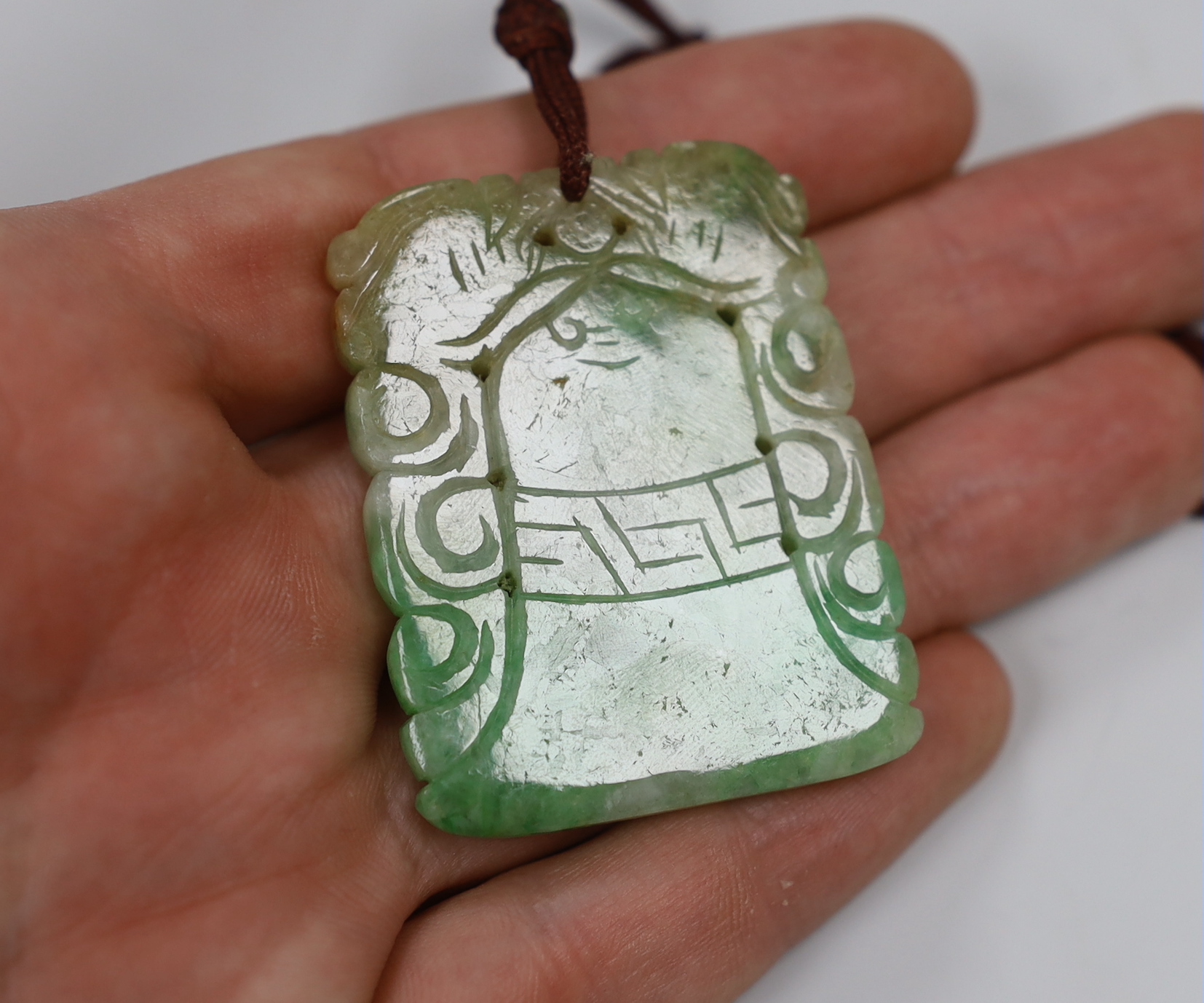 Two jadeite pendants and a handle tip